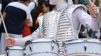 A performer in futuristic attire playing LED drums at a LED Drumming Parade