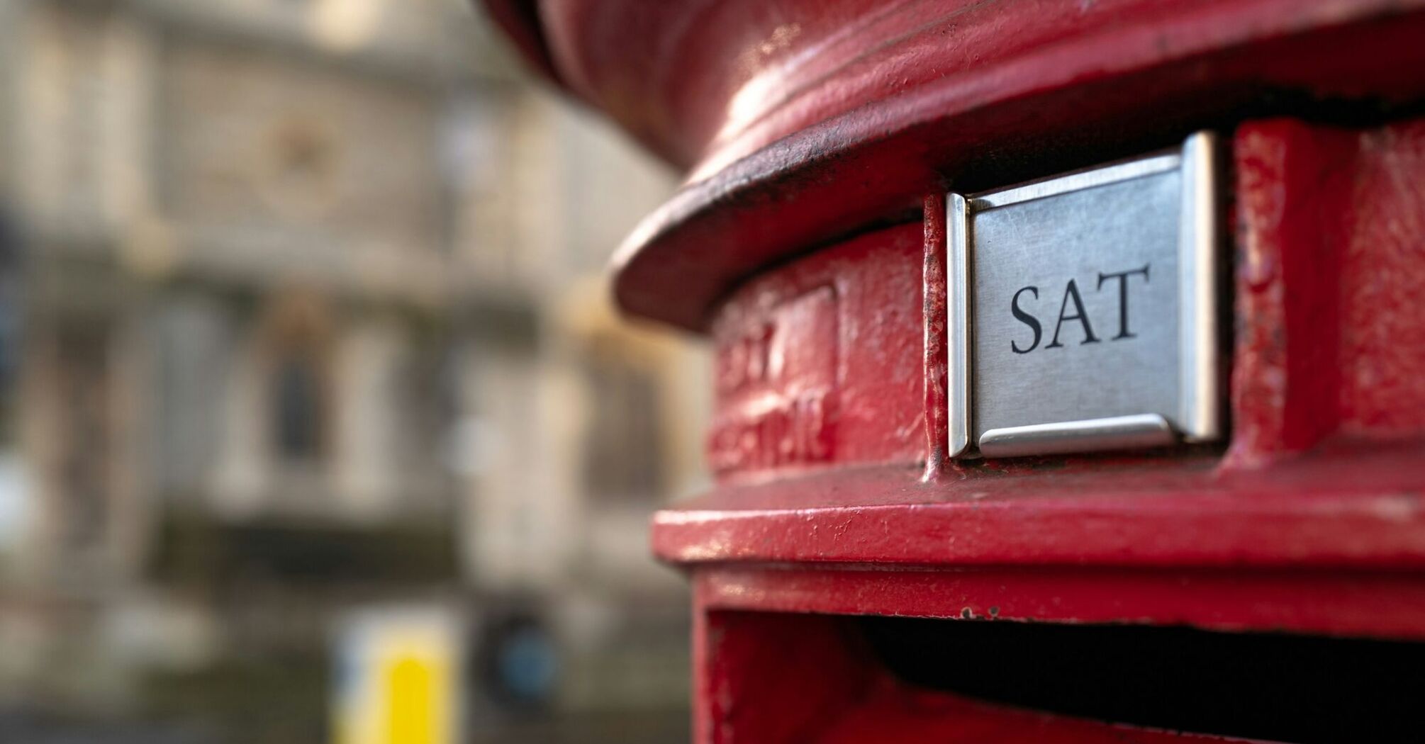 Close-up of a red British postbox with 'SAT' delivery indicator