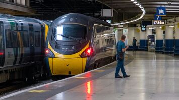 A stationary Avanti West Coast train at a platform in a modern railway station with passengers waiting nearby