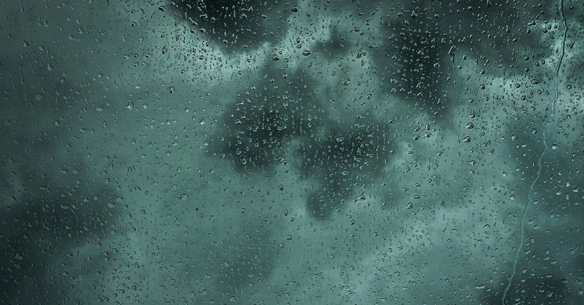 Rainy window with dark storm clouds in the background