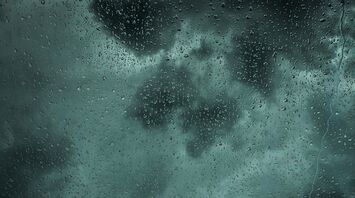 Rainy window with dark storm clouds in the background