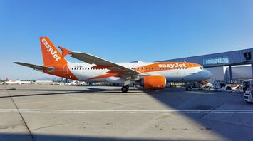 An easyJet airplane parked at an airport, ready for operations under a clear blue sky