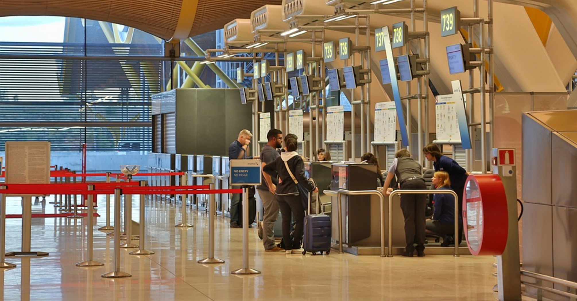 Travelers check in at an airport counter with staff assistance