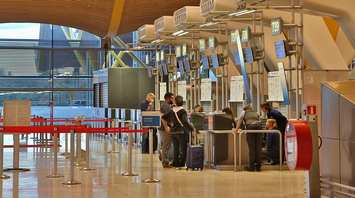 Travelers check in at an airport counter with staff assistance