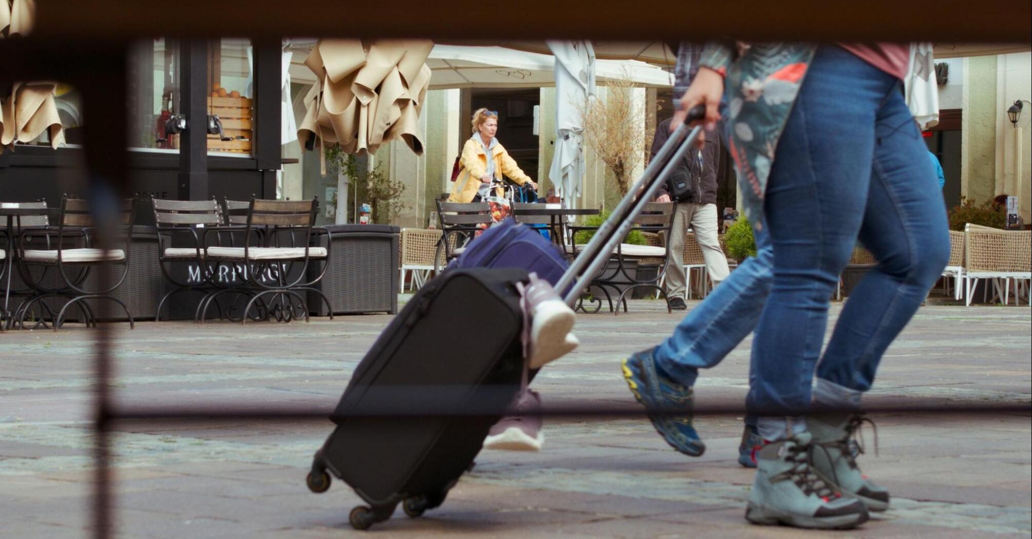 Traveler pulling a suitcase through a European square