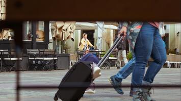 Traveler pulling a suitcase through a European square