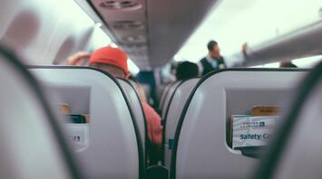 View of an airplane cabin with passengers seated and safety cards in seat pockets