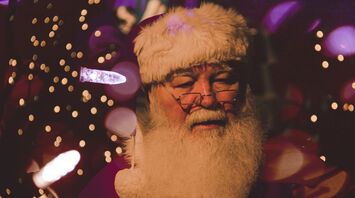 A close-up of Santa Claus with festive lights in the background, creating a warm and cheerful holiday atmosphere