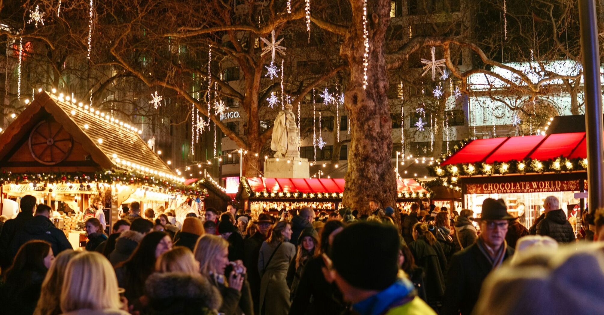 A bustling Christmas market with festive lights and decorations in the evening