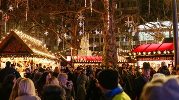 A bustling Christmas market with festive lights and decorations in the evening