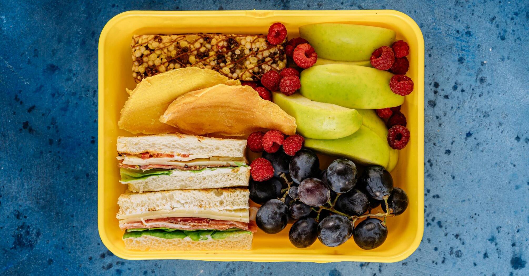 Lunch box with sandwiches, fruits, and snacks