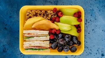 Lunch box with sandwiches, fruits, and snacks