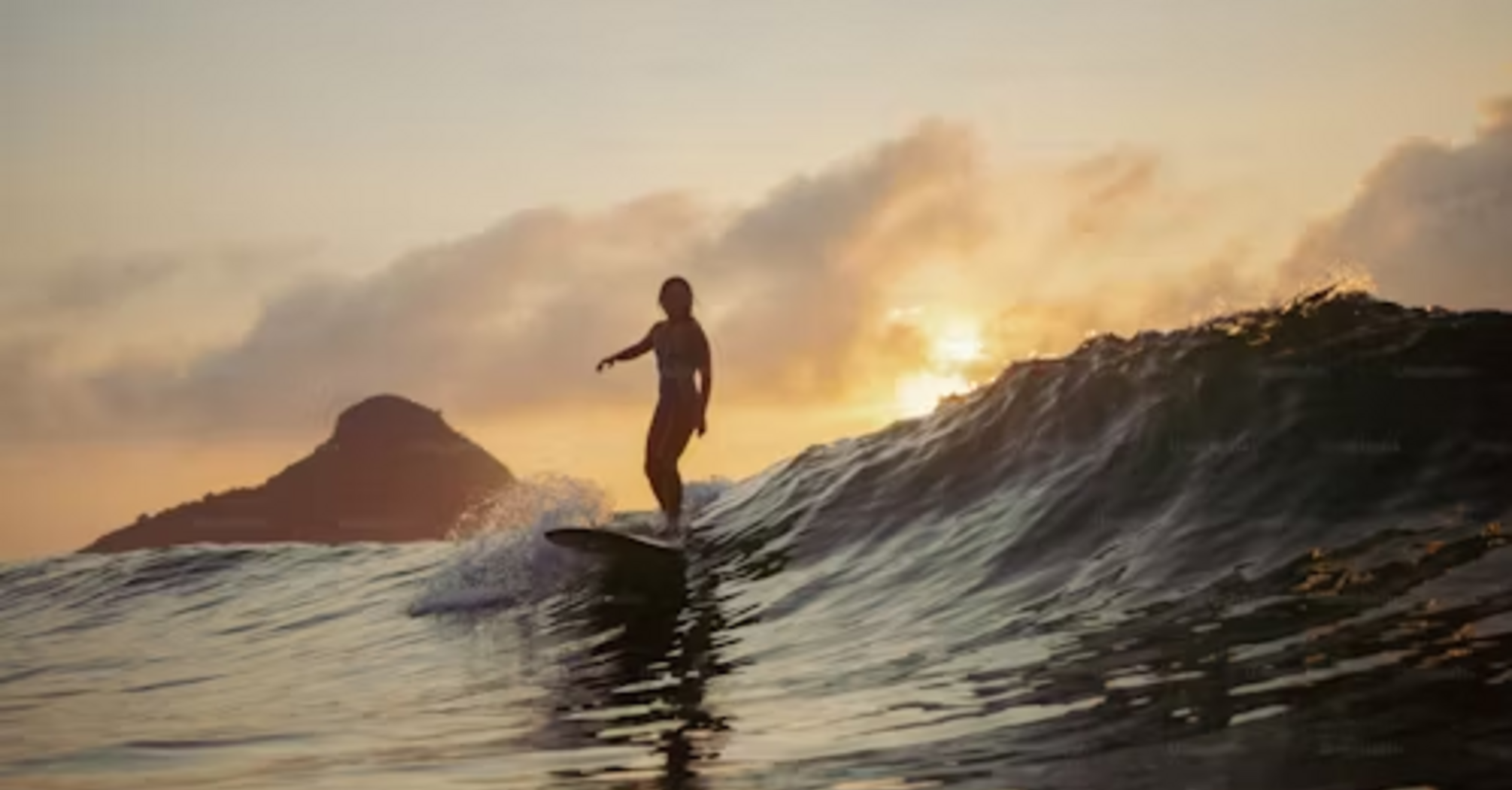 A surfer riding a wave at sunrise