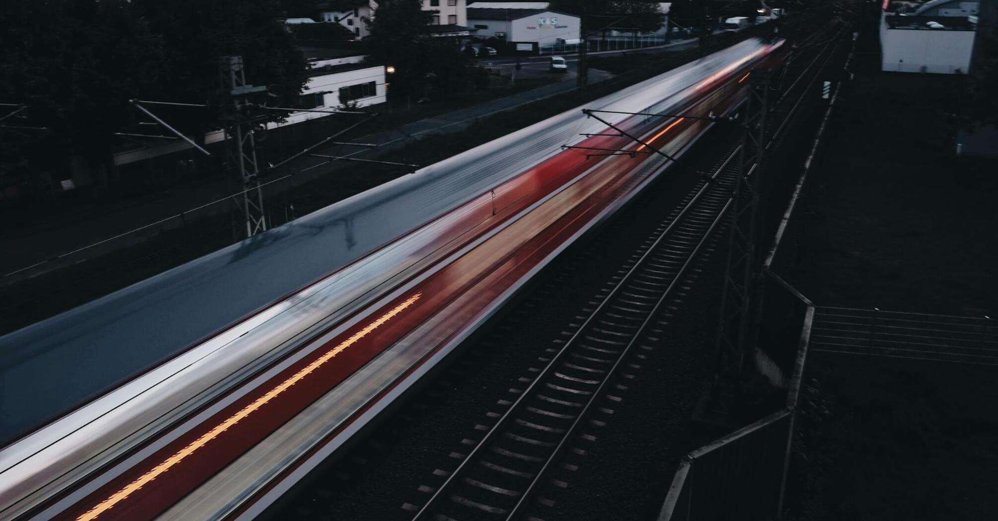 A fast-moving train passing through a suburban area at dusk