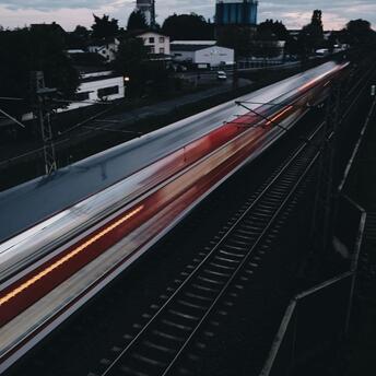 A fast-moving train passing through a suburban area at dusk
