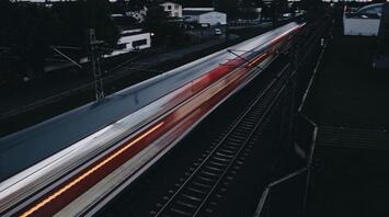 A fast-moving train passing through a suburban area at dusk