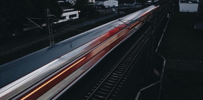 A fast-moving train passing through a suburban area at dusk