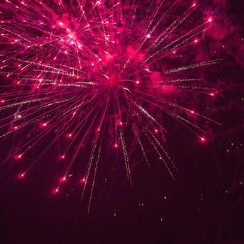 Bright red fireworks lighting up the night sky with dazzling trails