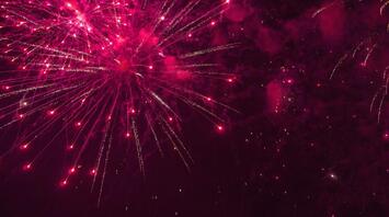 Bright red fireworks lighting up the night sky with dazzling trails