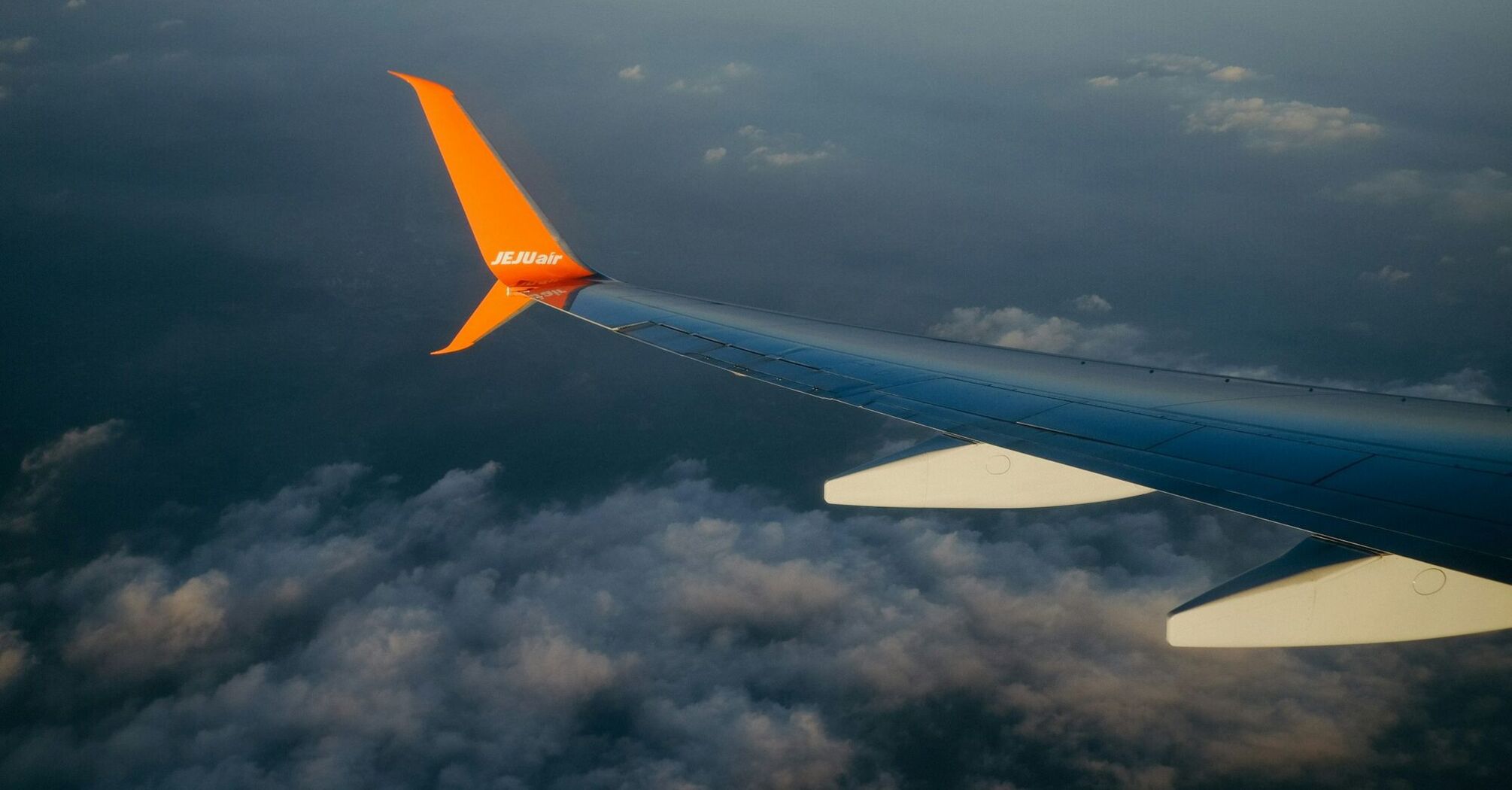 Jeju Air airplane wing in flight over clouds