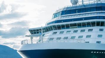 A cruise ship navigating serene waters under a cloudy sky