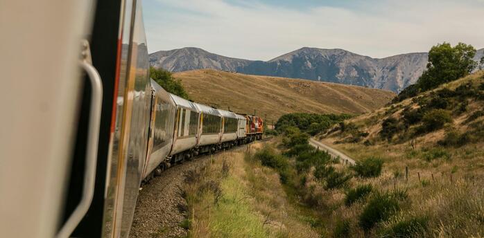 A scenic train journey through rolling hills and mountain