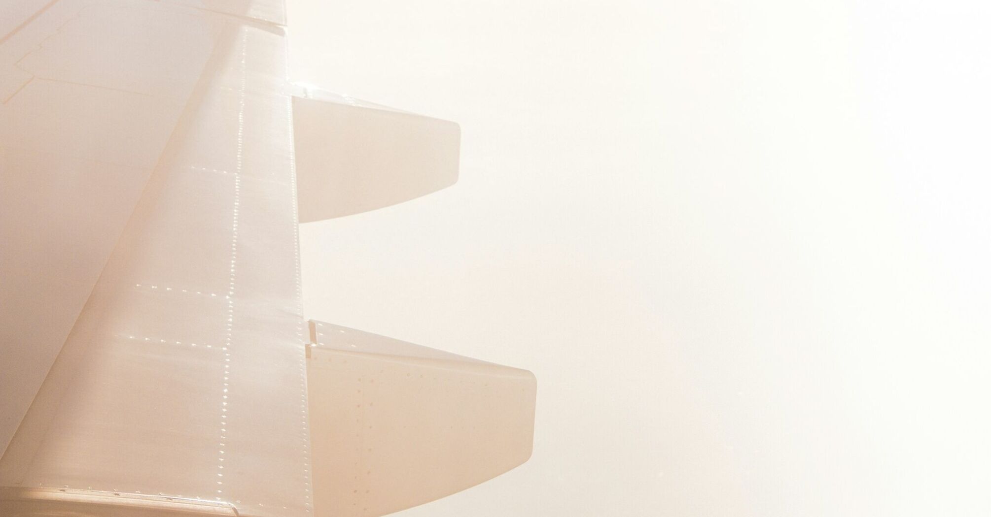 A close-up view of an airplane wing against a hazy sky