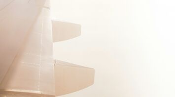 A close-up view of an airplane wing against a hazy sky
