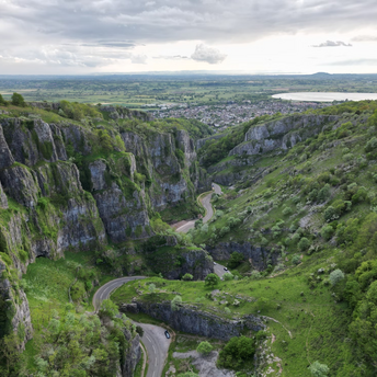 A view of Cheddar Gorge in Somerset, England, showcasing steep cliffs and winding roads surrounded by lush greenery