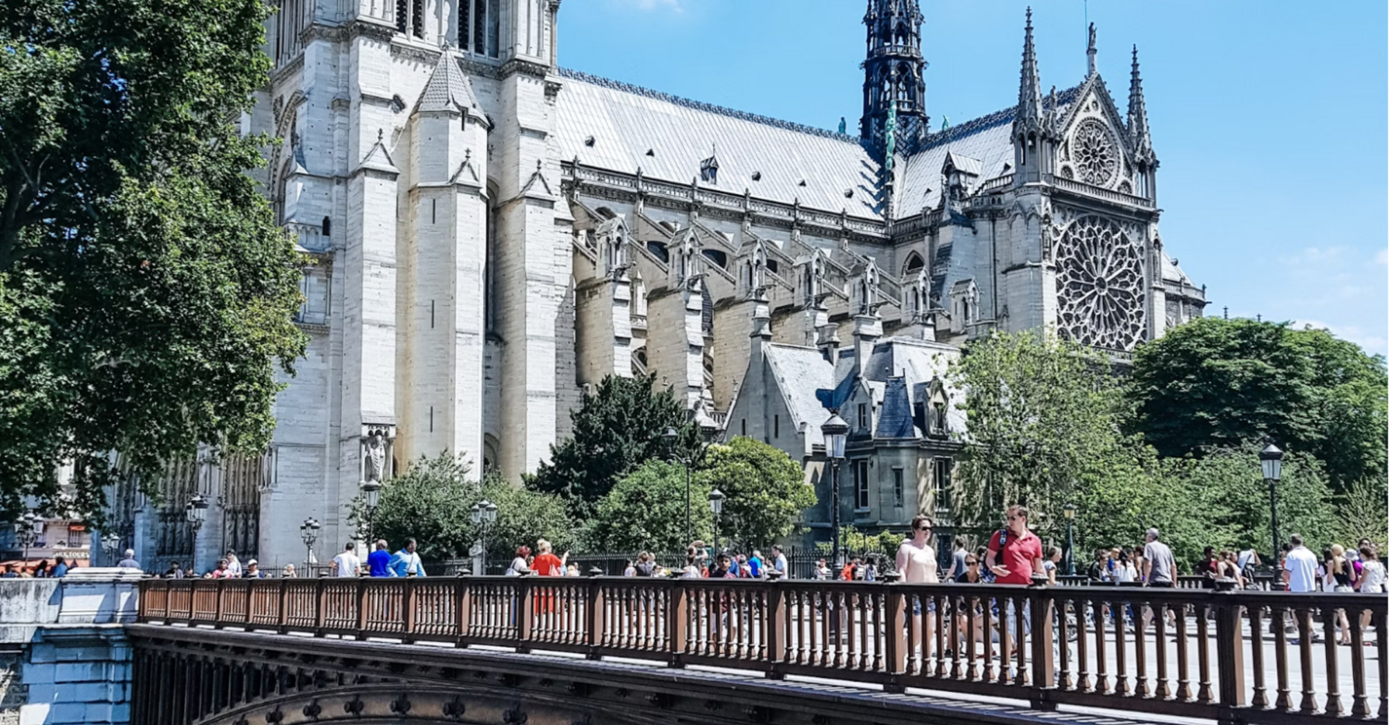 Notre-Dame Cathedral with a bridge in foreground on a sunny day