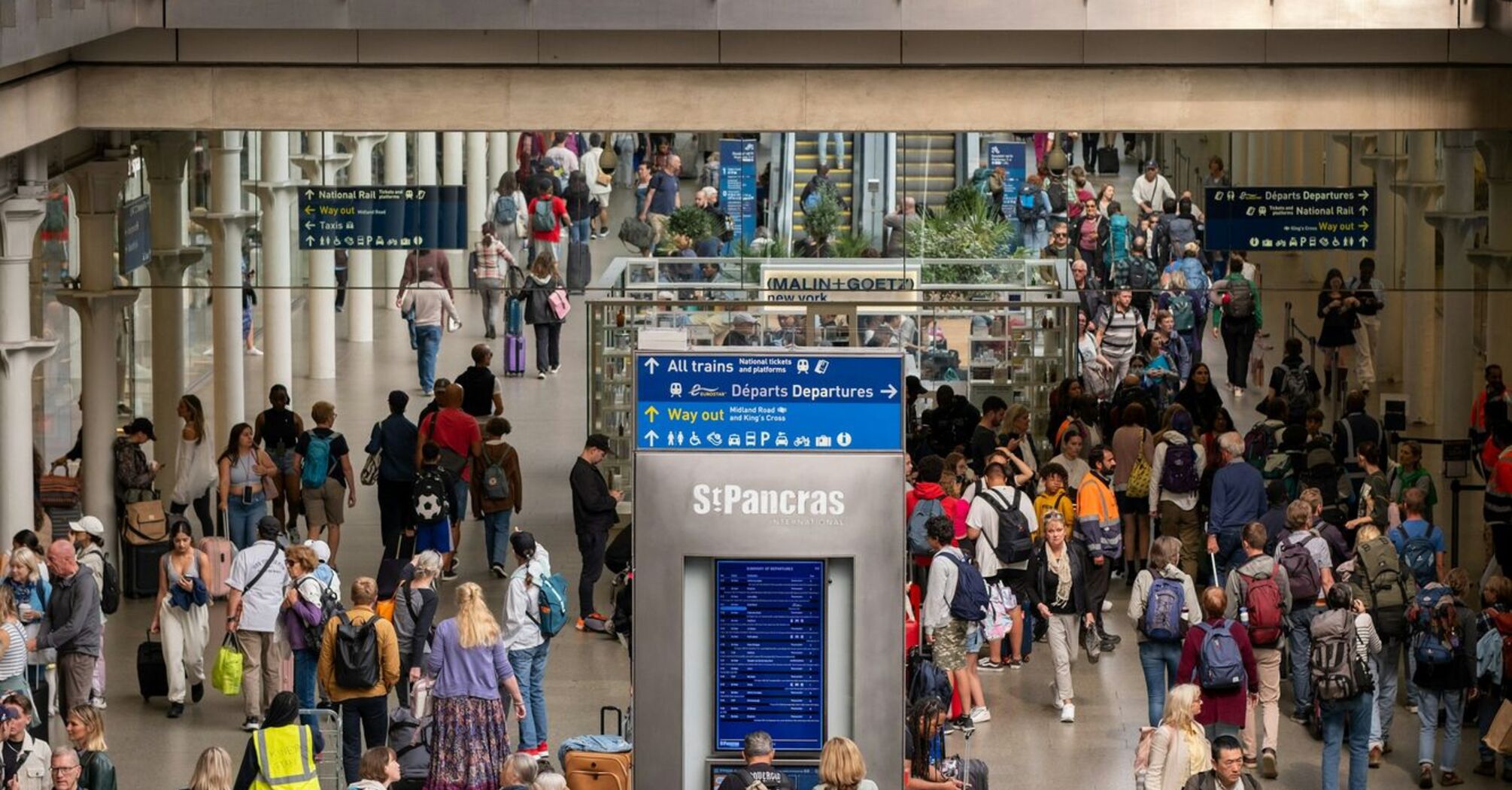 A crowded train station in London with travelers navigating busy platforms and waiting areas