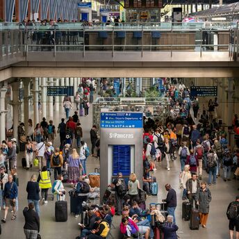 A crowded train station in London with travelers navigating busy platforms and waiting areas