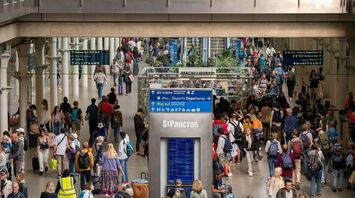 A crowded train station in London with travelers navigating busy platforms and waiting areas