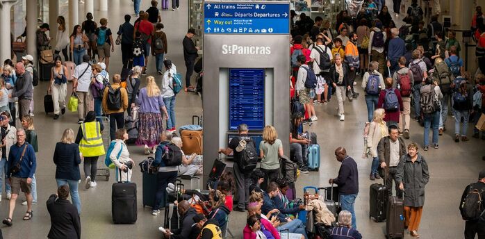 A crowded train station in London with travelers navigating busy platforms and waiting areas