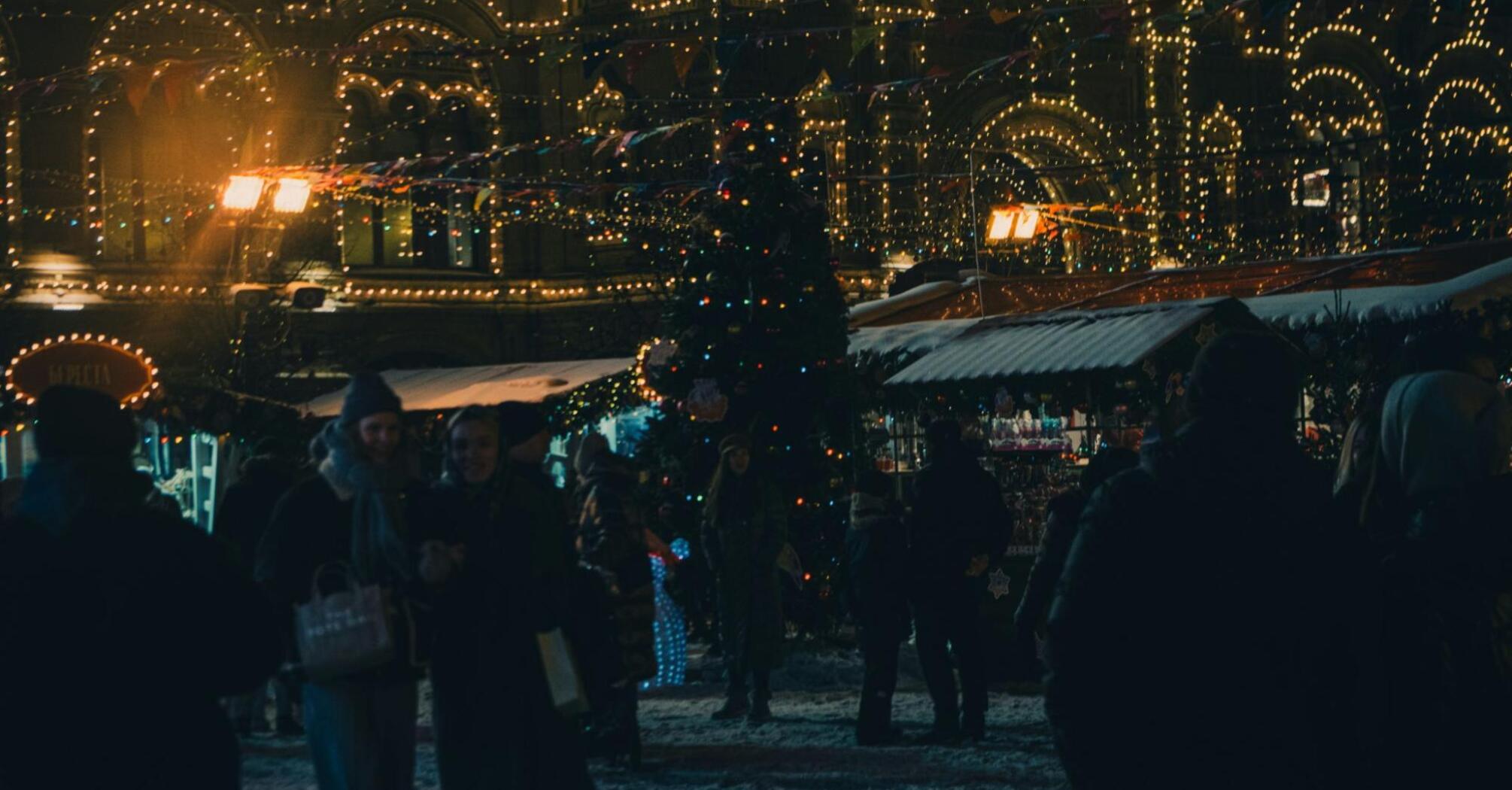 A festive night market with Christmas lights and decorations in a snowy city square