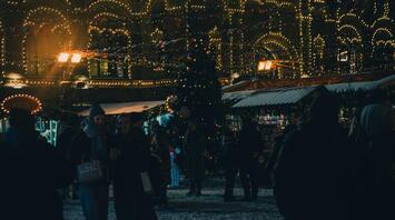 A festive night market with Christmas lights and decorations in a snowy city square