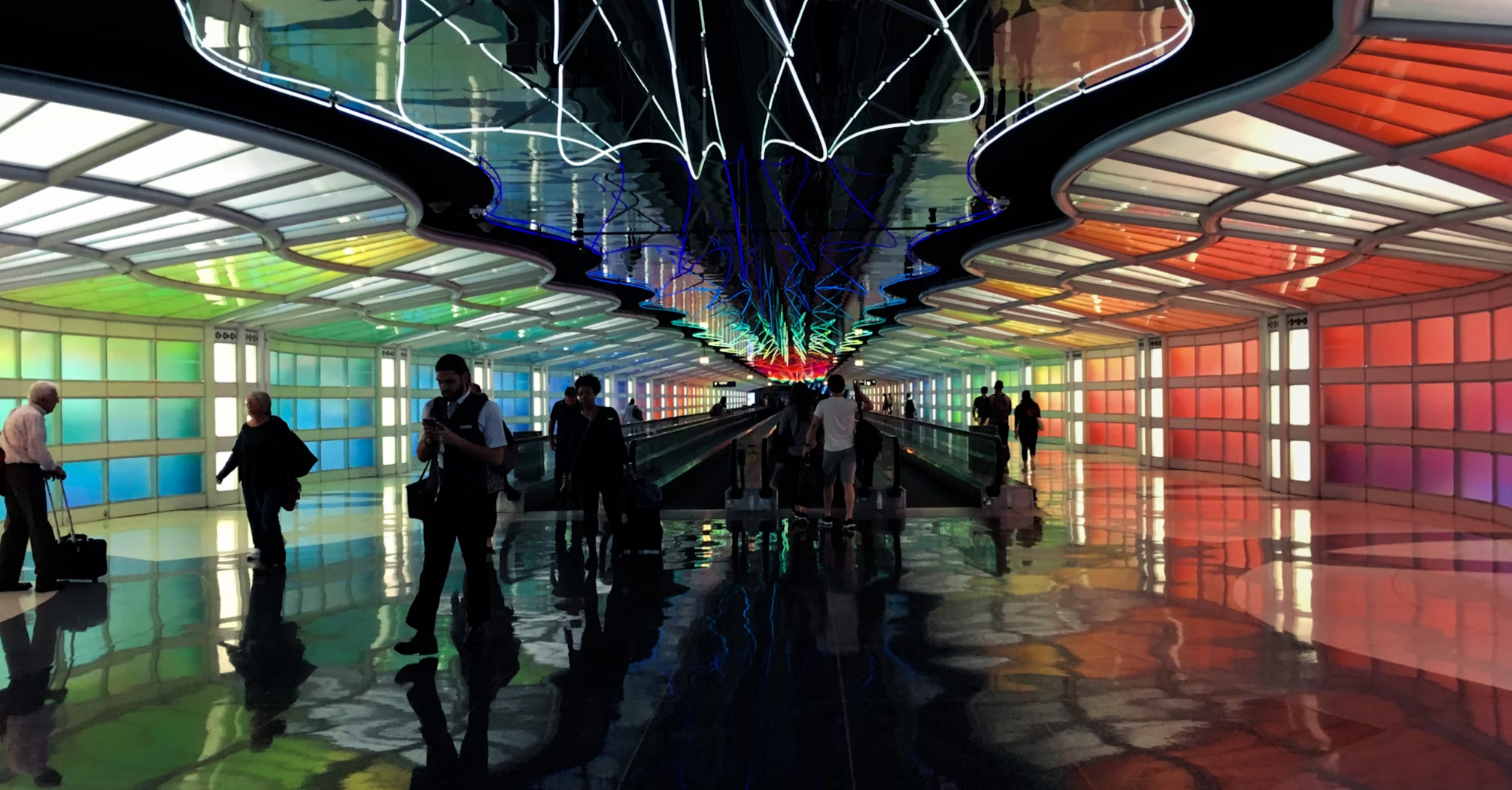 Colorful illuminated airport walkway with passengers in motion