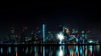City skyline at night with fireworks and reflections on water