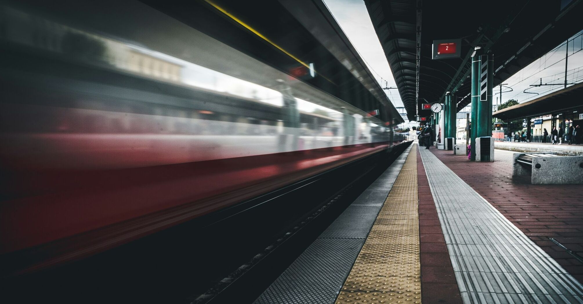 A high-speed train passing through a modern train station platform