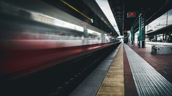 A high-speed train passing through a modern train station platform