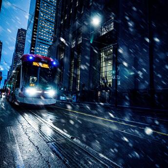A tram navigating through a snowy city street at night