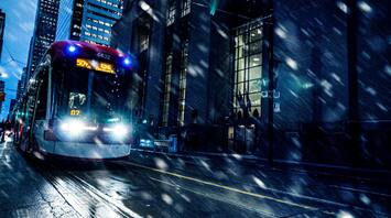 A tram navigating through a snowy city street at night