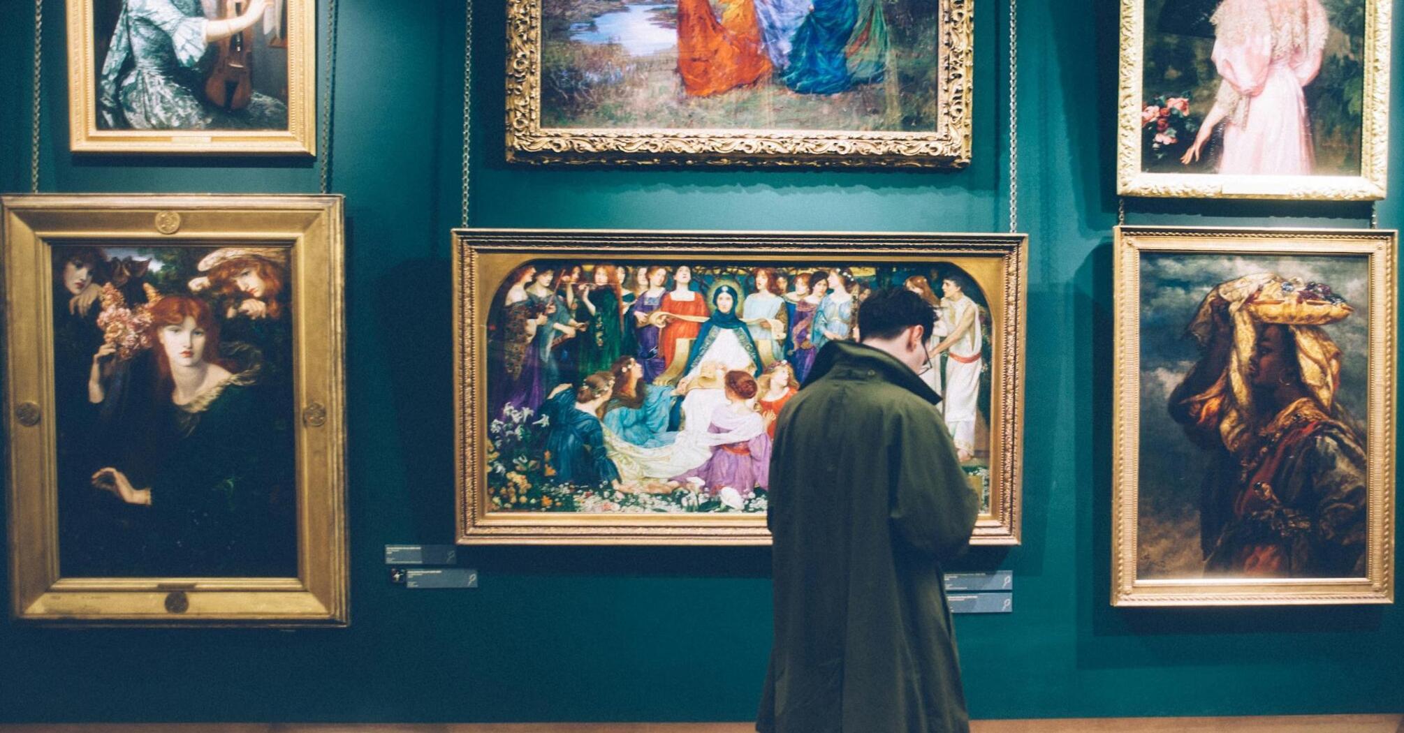 A person observing vibrant paintings in a gallery setting