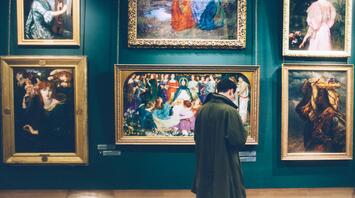 A person observing vibrant paintings in a gallery setting