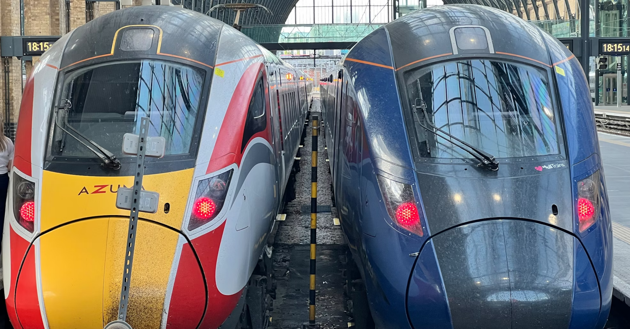 Two modern Azuma and Lumo trains parked at King's Cross Station under a glass-covered roof