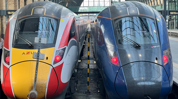 Two modern Azuma and Lumo trains parked at King's Cross Station under a glass-covered roof