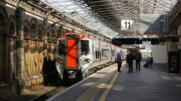 A Transport for Wales train at a station platform with passengers waiting nearby