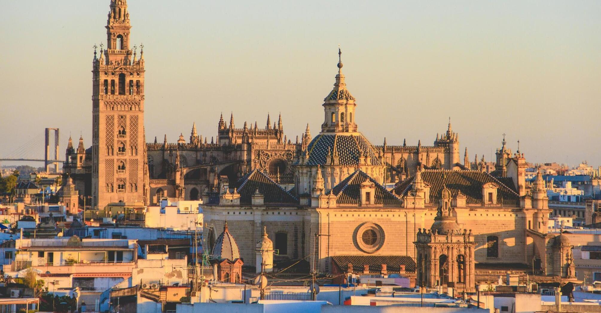 A scenic view of Seville Cathedral and La Giralda tower at sunset, symbolizing Spain's rich cultural heritage