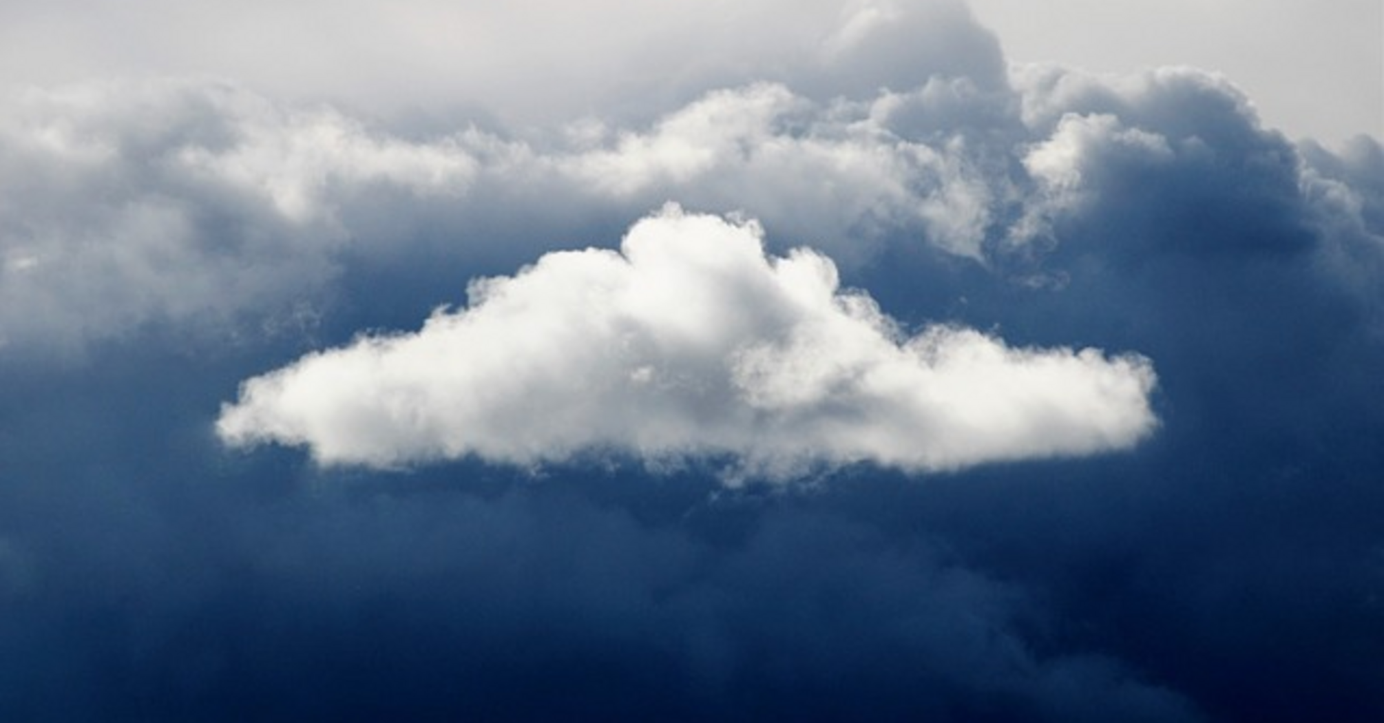 A fluffy white cloud surrounded by dark storm clouds in the sky