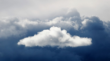 A fluffy white cloud surrounded by dark storm clouds in the sky